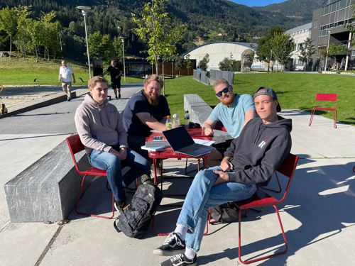 Studentar sitt i sola utanfor campus Sogndal